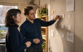Zwei Redaktionsfachleute prüfen in einem österreichischen Content-Studio einen KI-gestützten Veröffentlichungsablauf an einem Planungsboard.